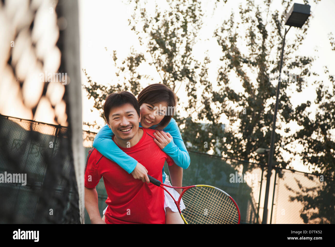 Boyfriend holding his girlfriend next to the tennis net Stock Photo
