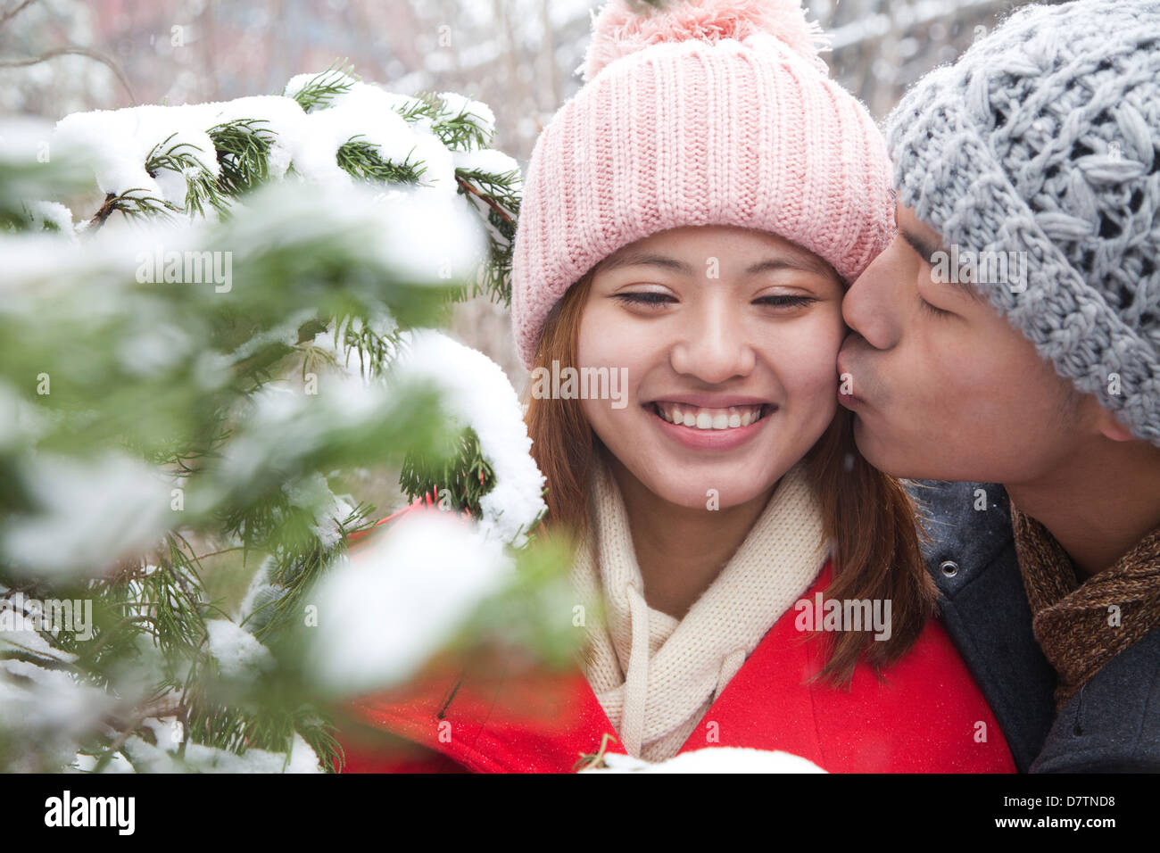 Young man kissing young woman in park in snow Stock Photo - Alamy