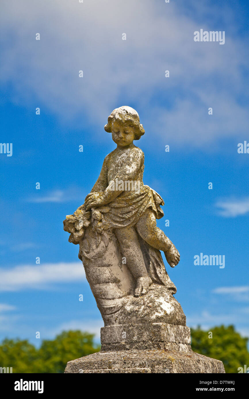 A stone statue of a young girl in a cemetery. Stock Photo