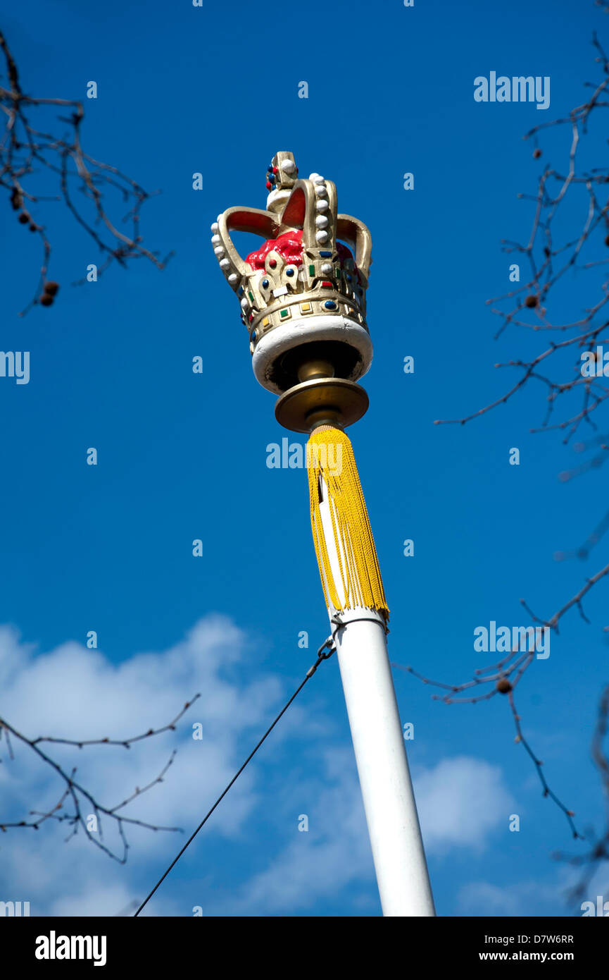 A ceremonial painted crown on top of a flag pole with yellow tassel decoration in London Stock Photo
