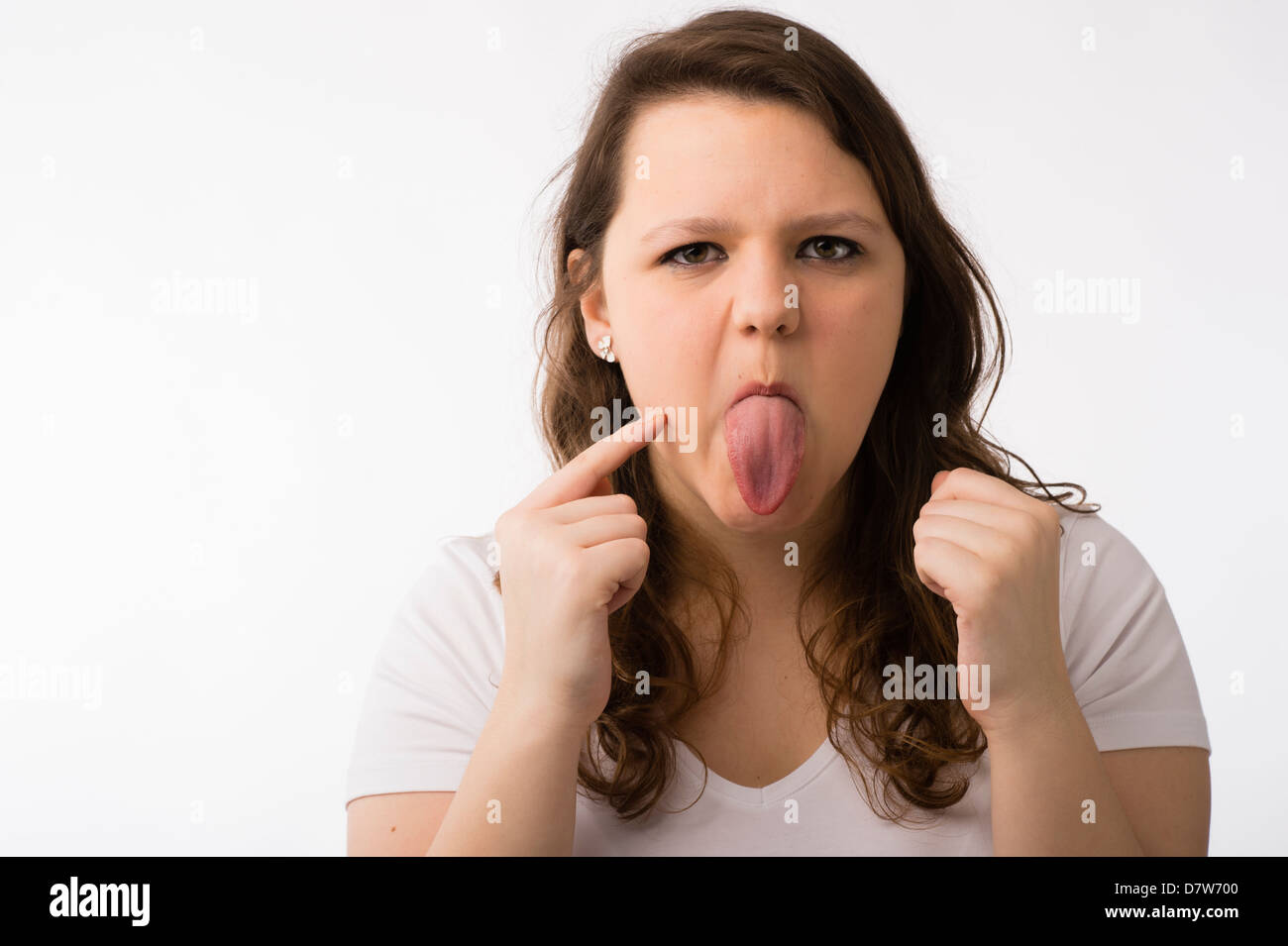 A young brunette teenage Caucasian girl checking her face and complexion sticking out her tongue Stock Photo