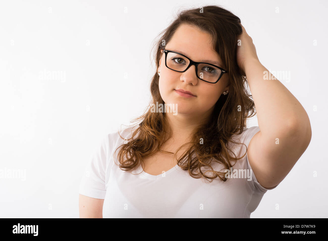 A young brunette teenage Caucasian girl wearing glasses confused concerned scratching her head Stock Photo