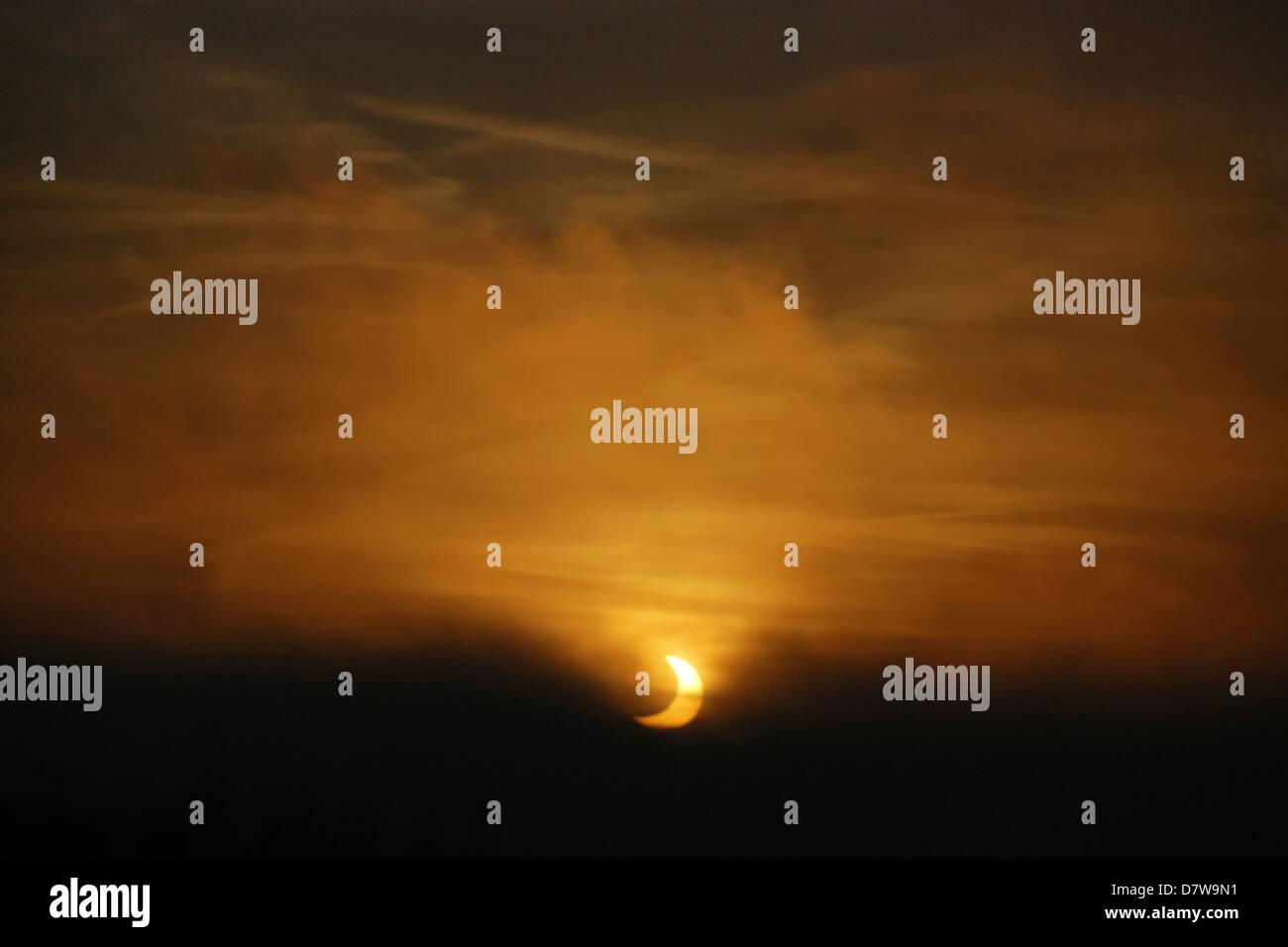 Partial eclipse of the sun seen through fog during sunrise Stock Photo