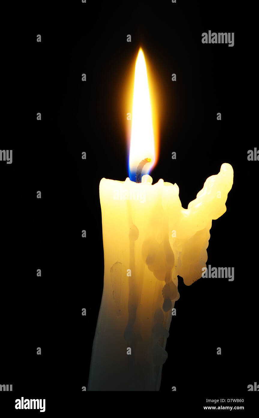 White candle with wax running down side of candle against a black