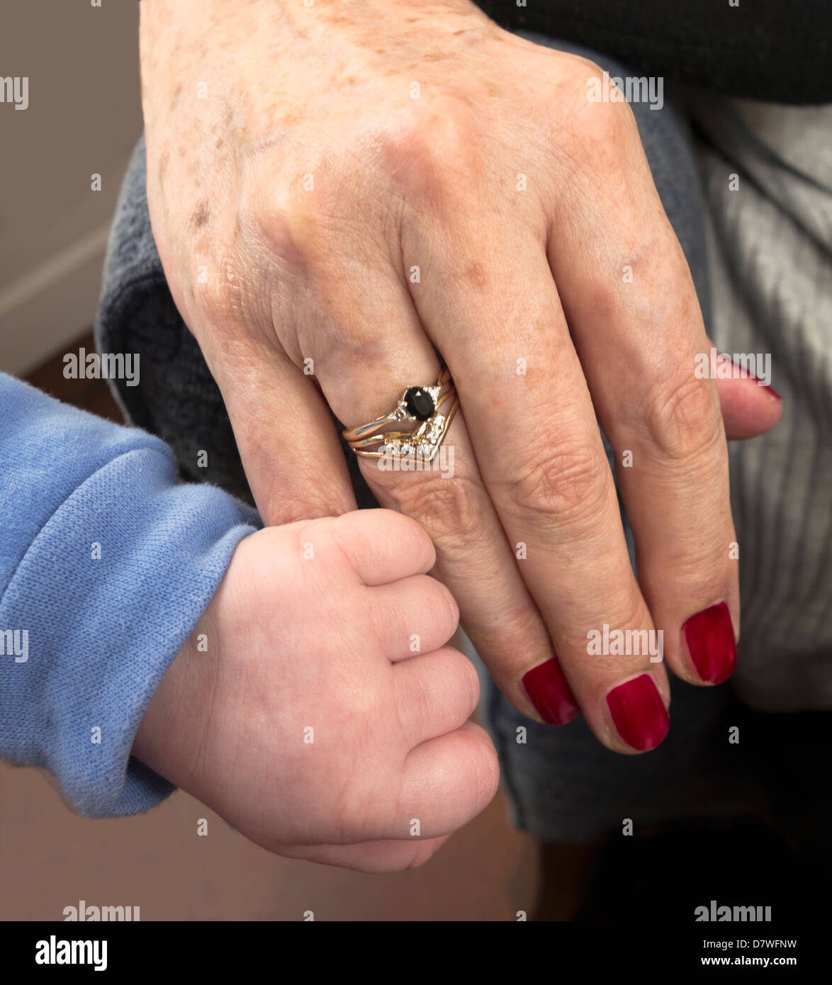A baby's hand clutching an older woman's little finger Stock Photo