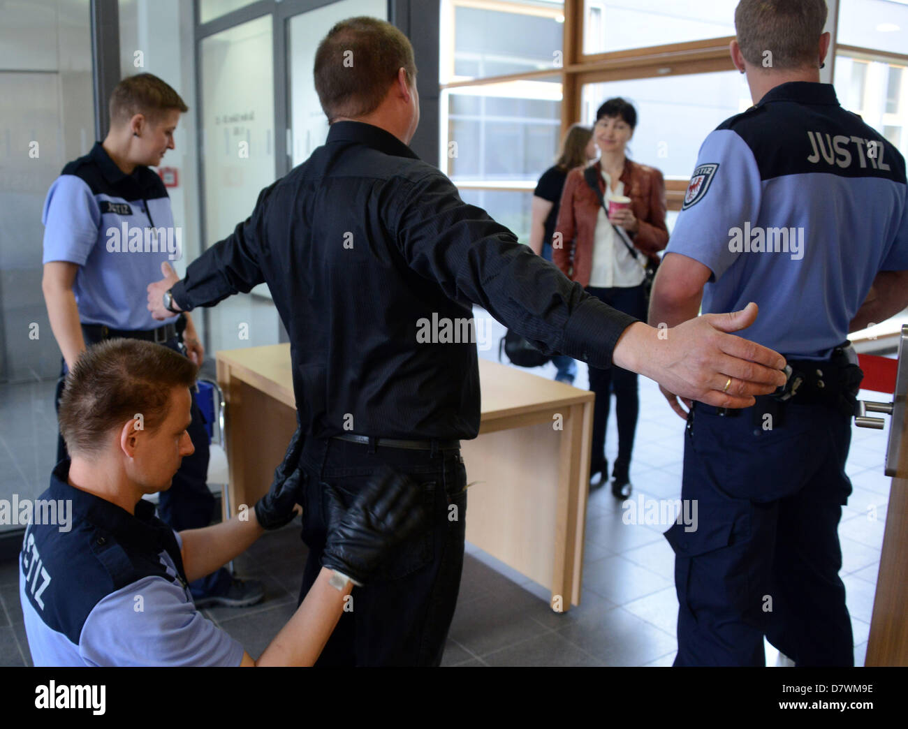 Court officers frisk a visitor to the trial outside of a courtroom at the regional court in Potsdam, Germany, 14 May 2013. The court is hearing the charges against three members of the 'Hells Angels Motorcylce Club Oder-City' for attempted murder. Photo: BERND SETTNIK Stock Photo
