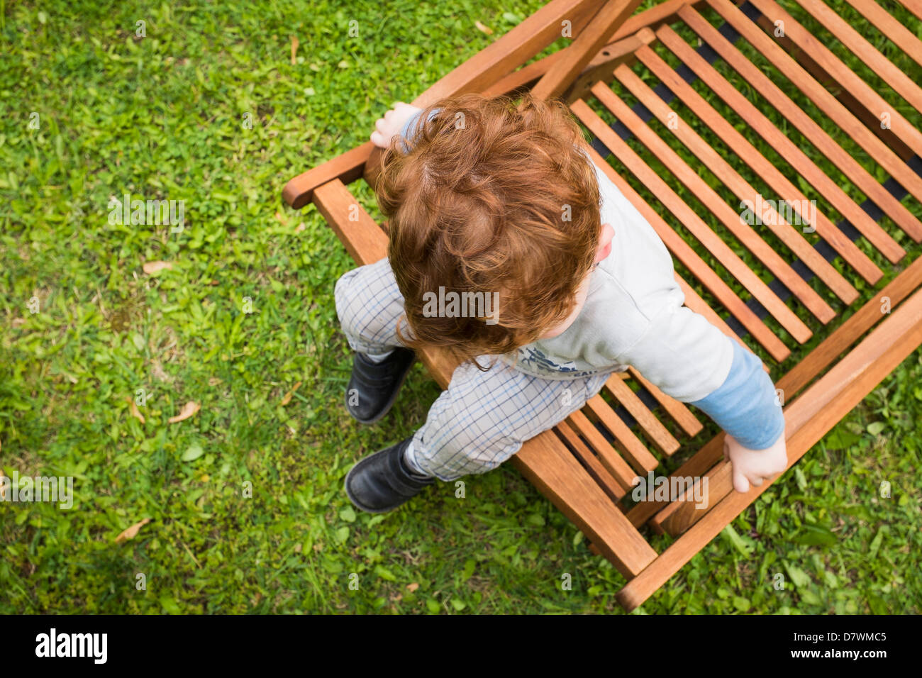 View of a 2-year old red haired boy sitting on deckchair. Taken from above Stock Photo