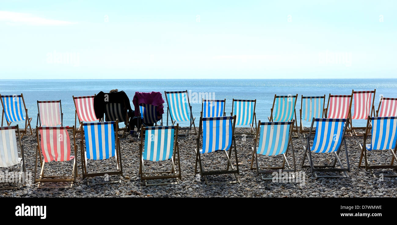 2 people sitting in deck chairs in Beer Devon England uk Stock Photo