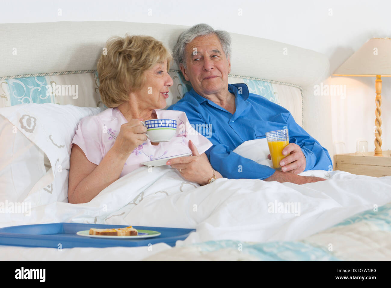 Elderly couple having breakfast in their bed Stock Photo