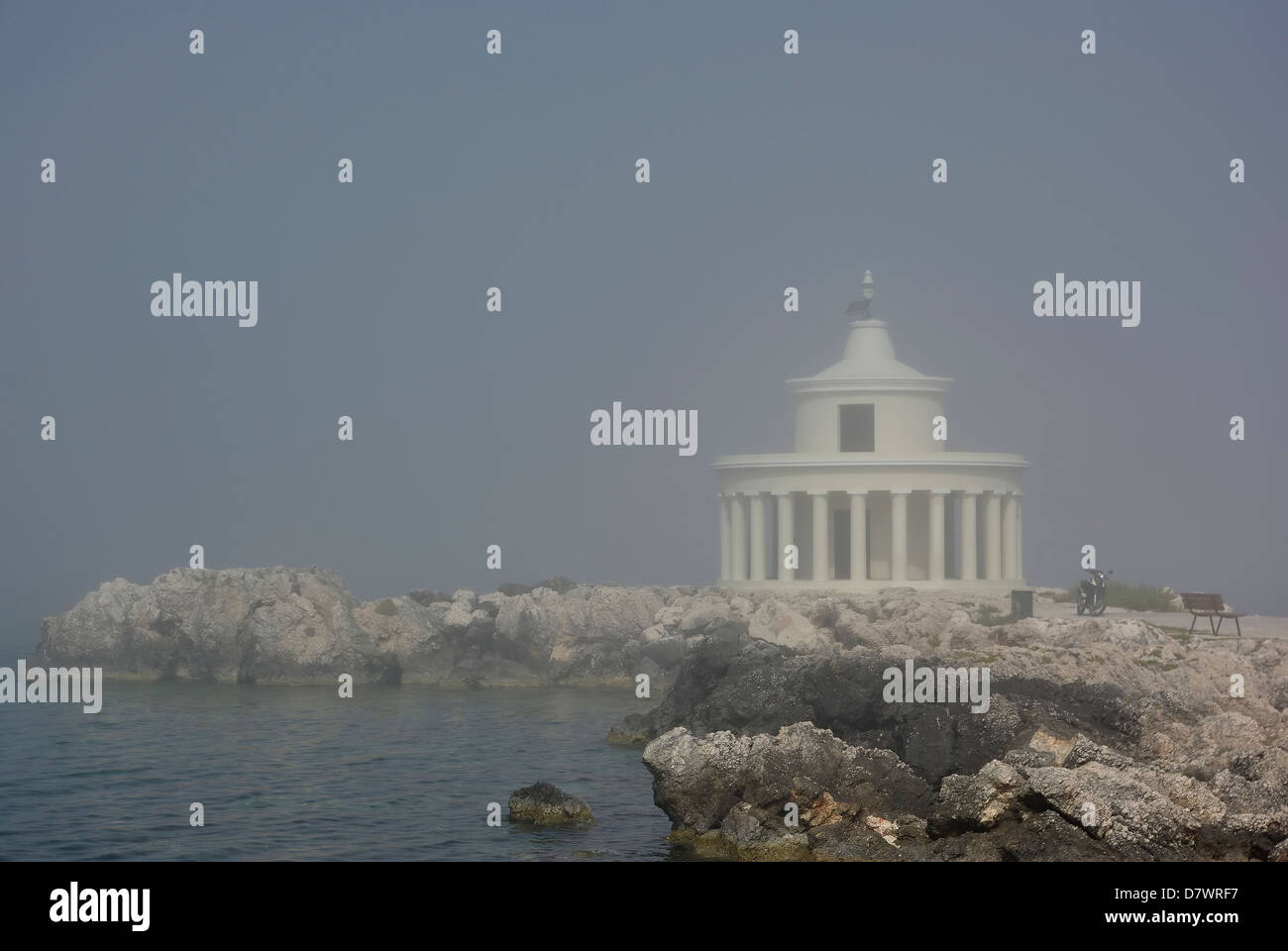 Blurred lighthouse and bench at bay entrance at foggy summer day. Stock Photo