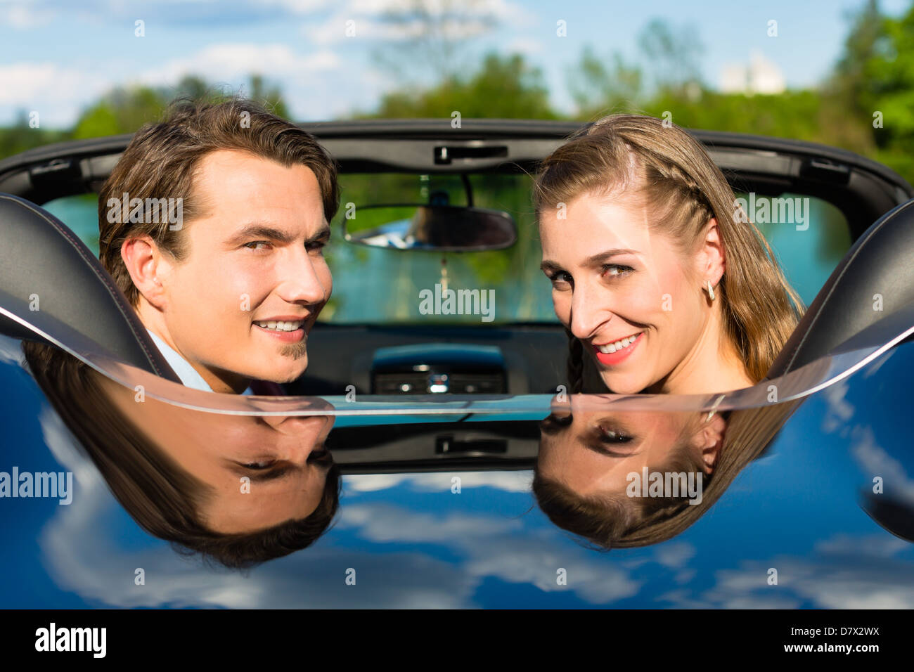 Young hip couple - man and woman - with cabriolet convertible car in summer on a day trip Stock Photo