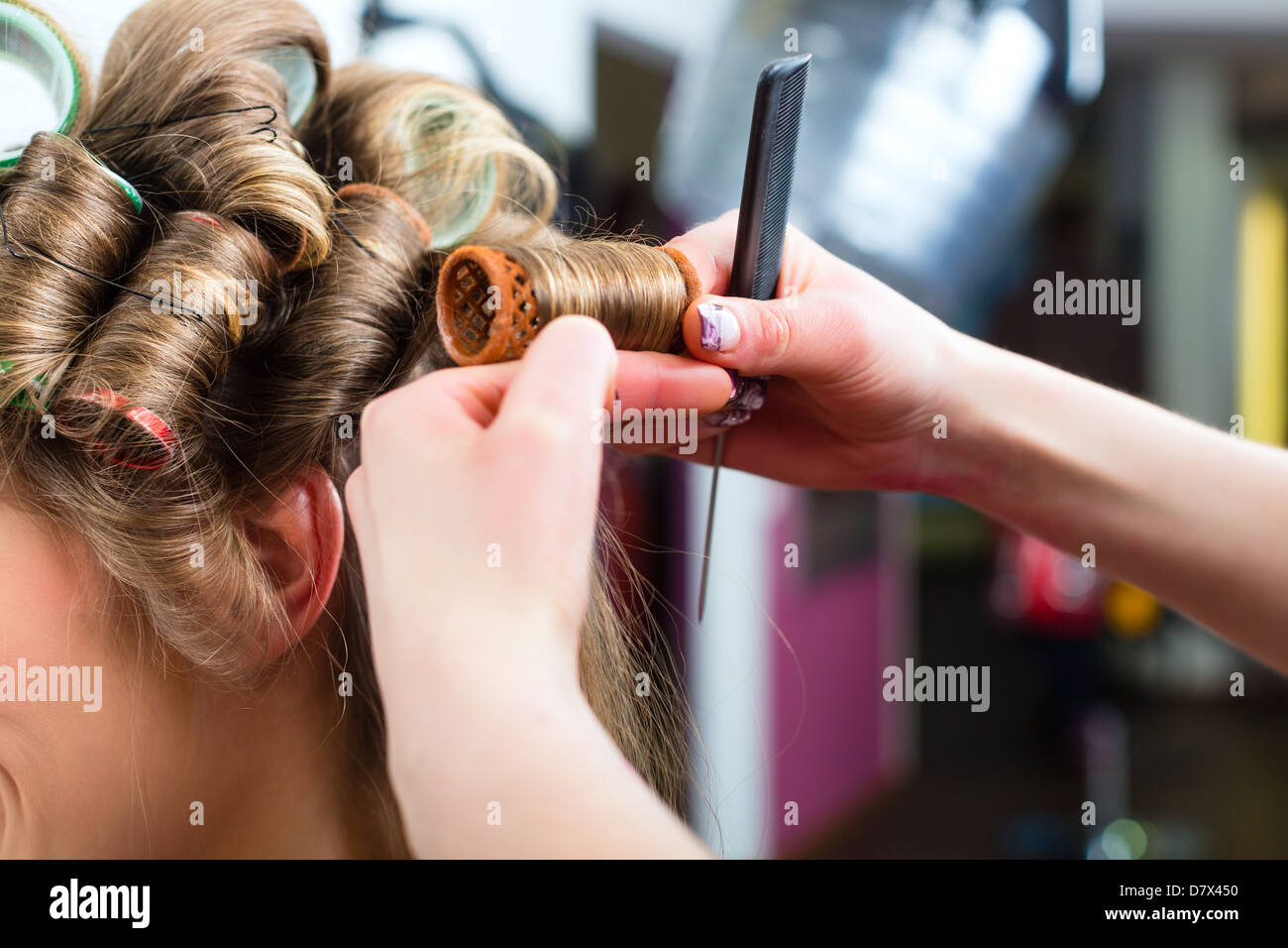 Hairdresser - hair stylist curling hairs, a female customer gets a haircut Stock Photo