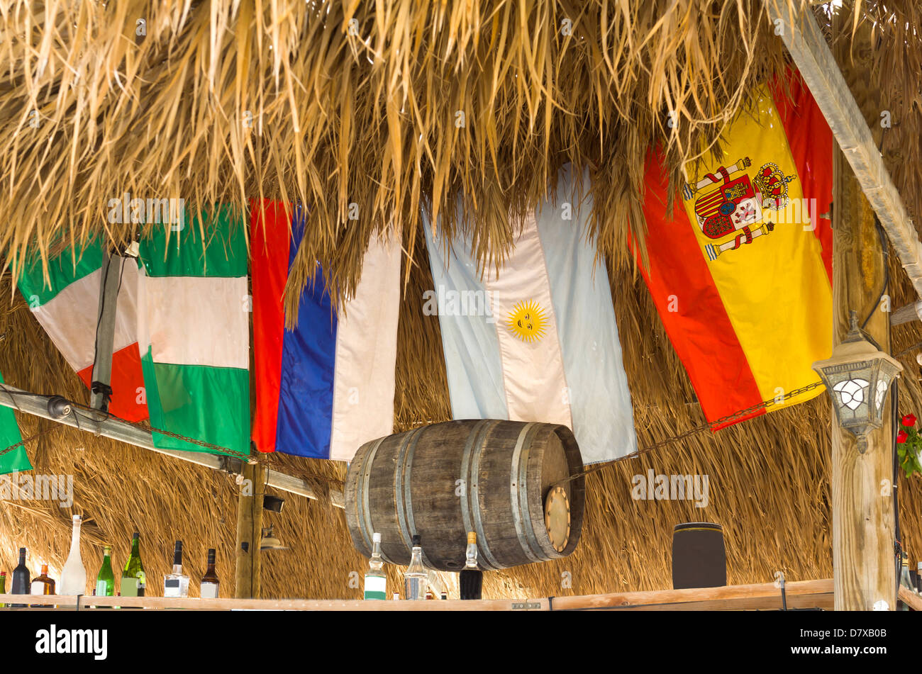 Flags in the bar under a roof of palm leaves Stock Photo