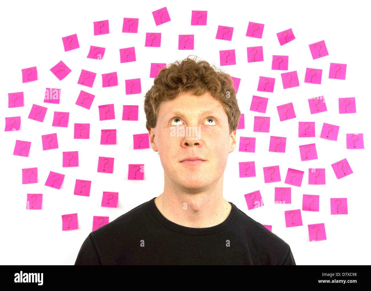 Young man with pink sticky notes and question marks thinking about decision making Stock Photo