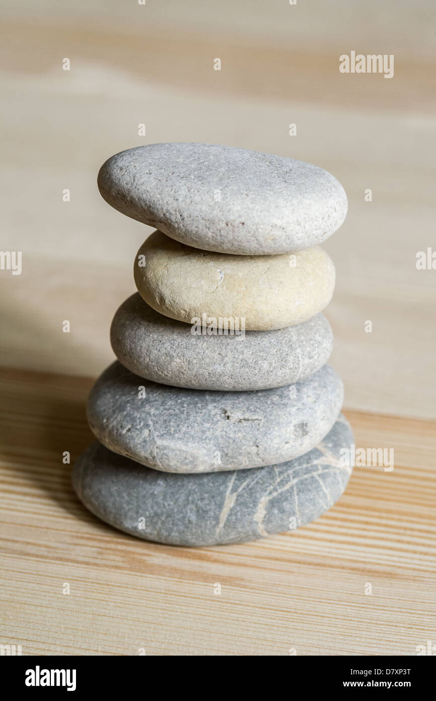 Five spa zen stones stacked on a light wood background Stock Photo