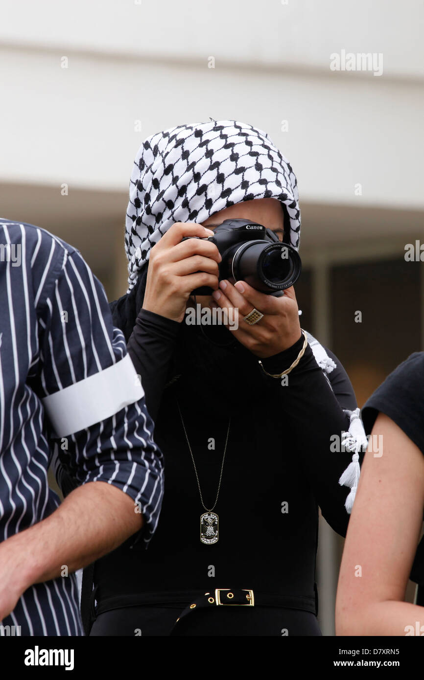 A young Arab woman wearing a traditional Kaffiye headgear photographing an event in Israel Stock Photo