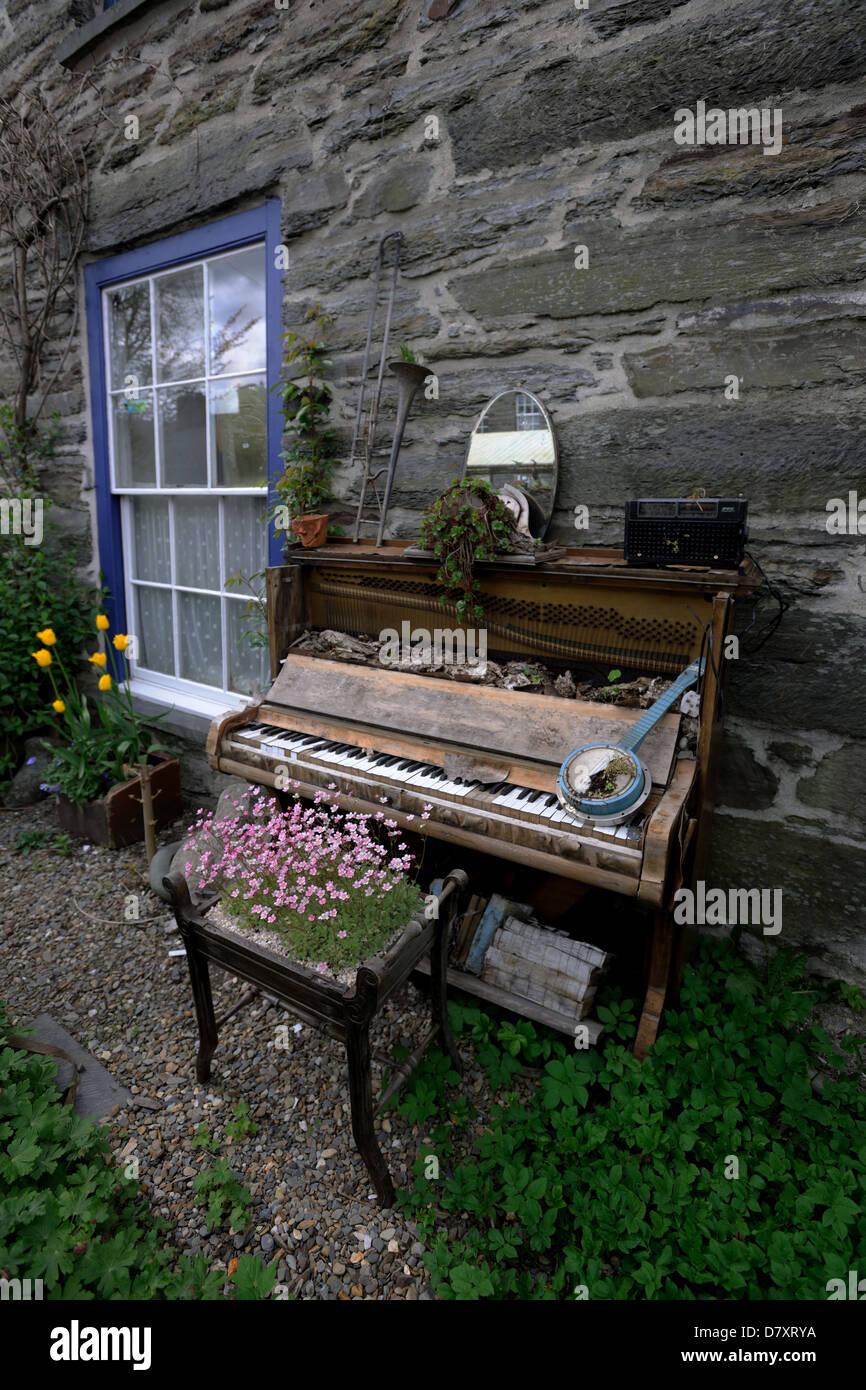 Broken piano used in a garden as display sculpture in Machynlleth,Wales Stock Photo