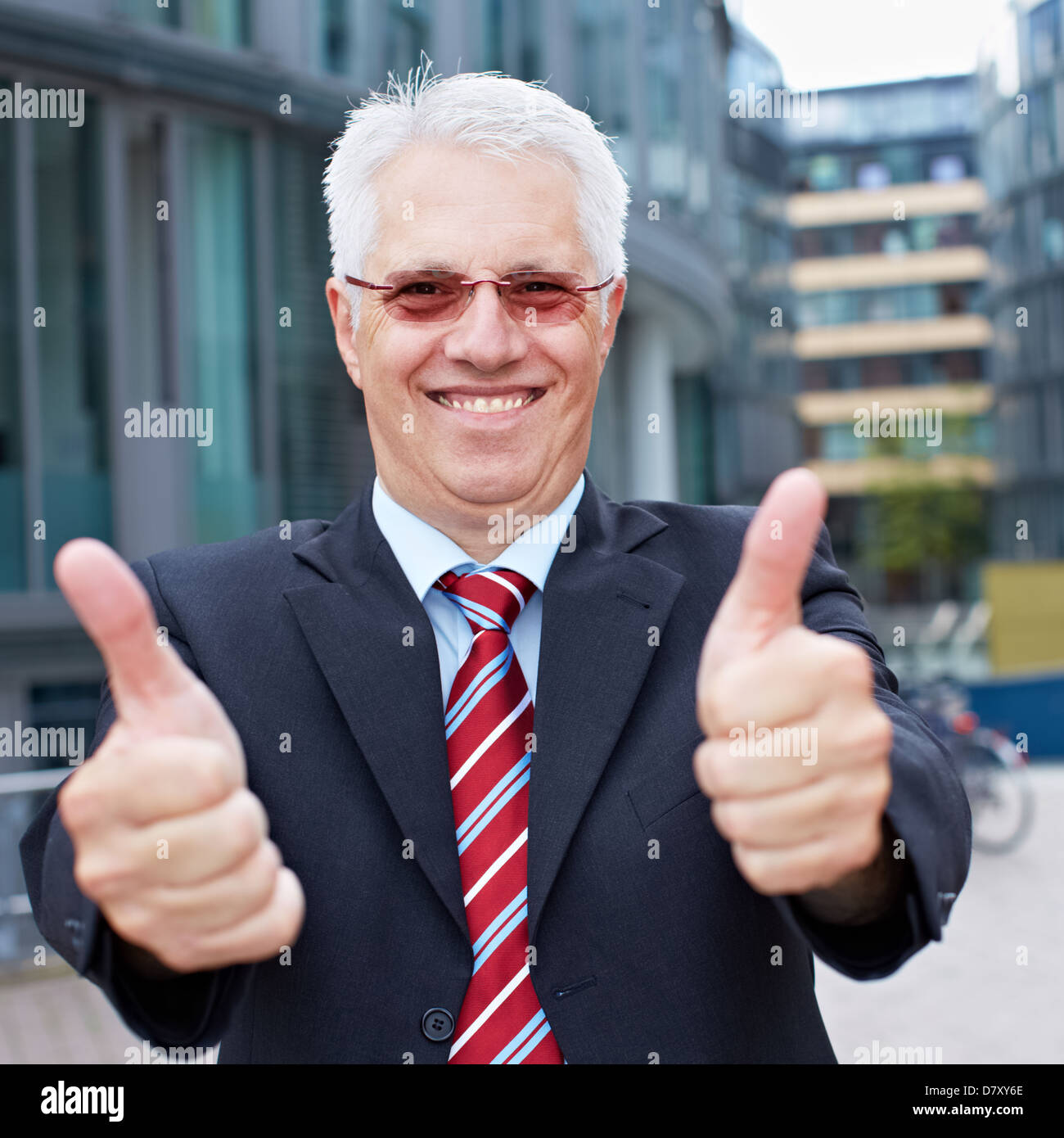 Happy senior business man holding his thumbs up outside the office Stock Photo