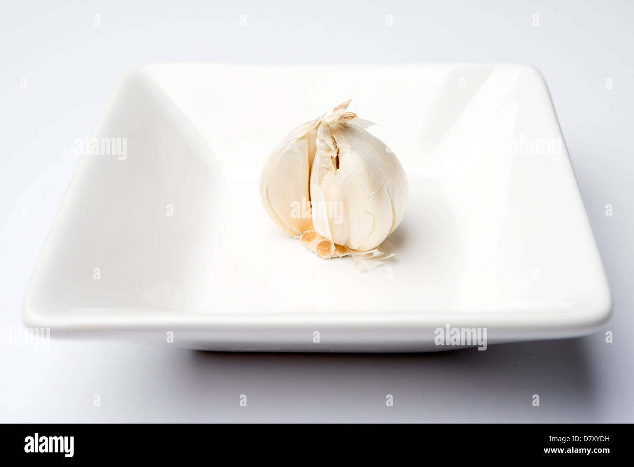 close up of a garlic bulb on a white plate Stock Photo