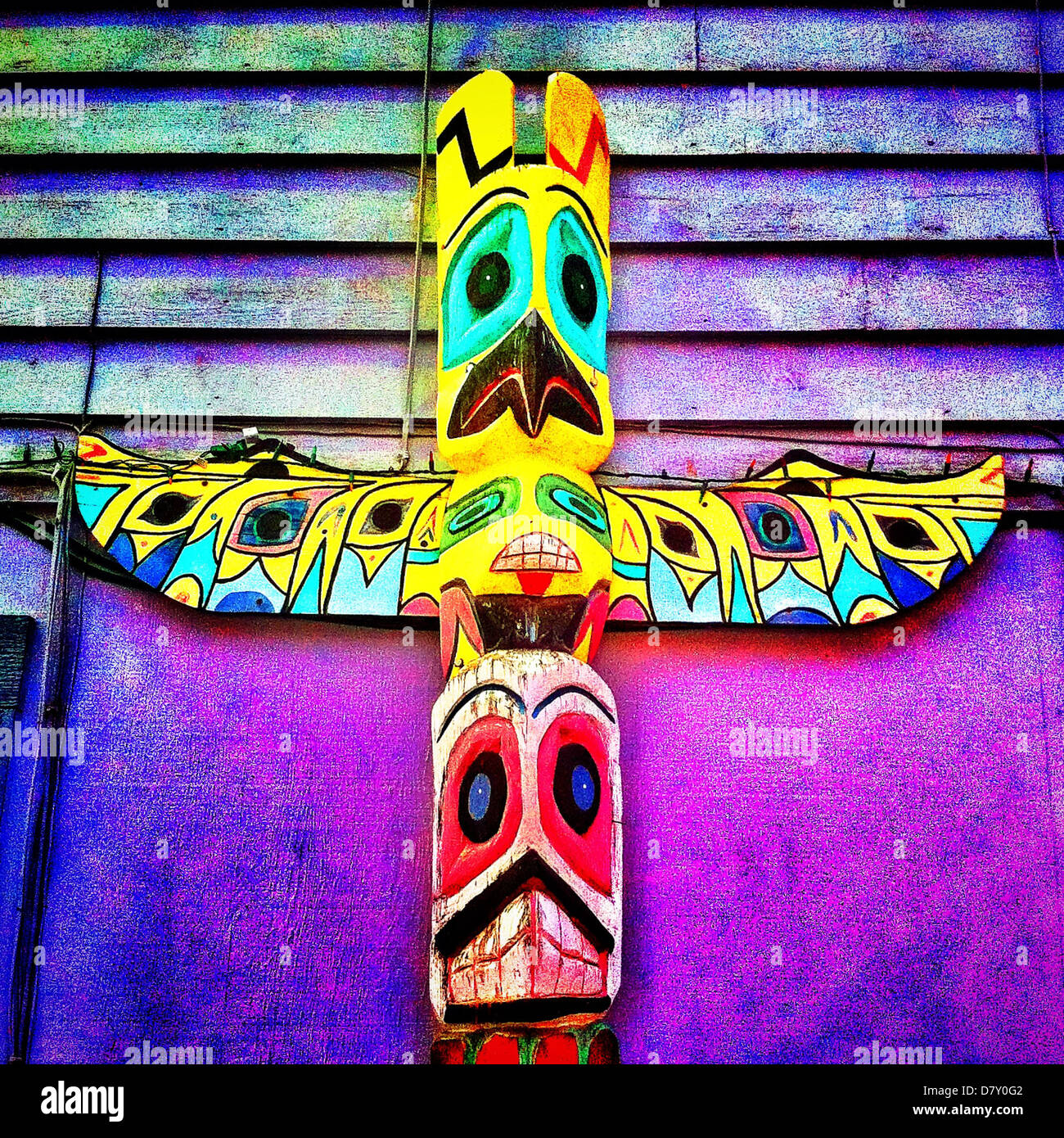 Colorful totem pole leaning on building Stock Photo