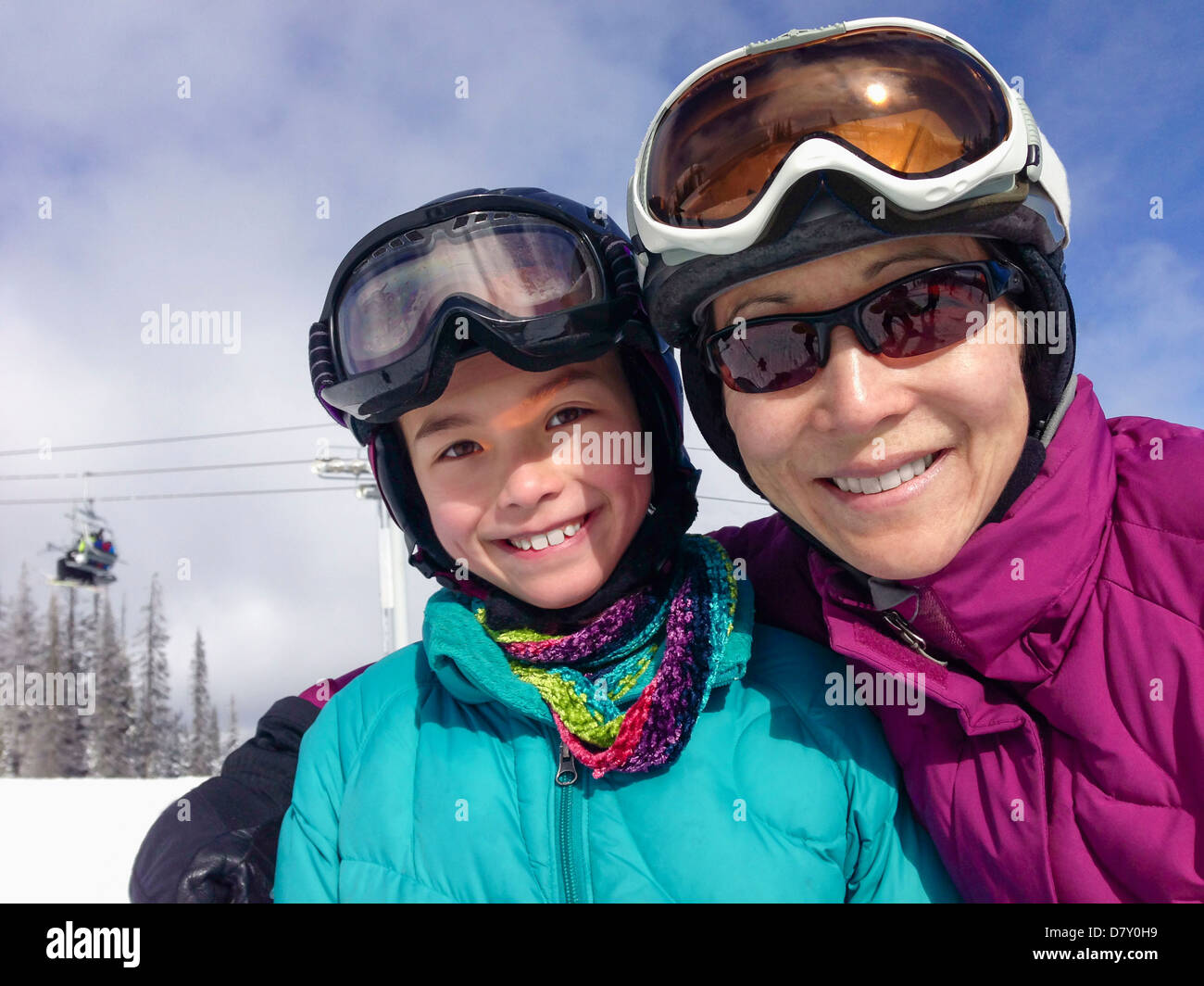 Mother and daughter wearing ski gear on mountain - Smartphone Captured Stock Image