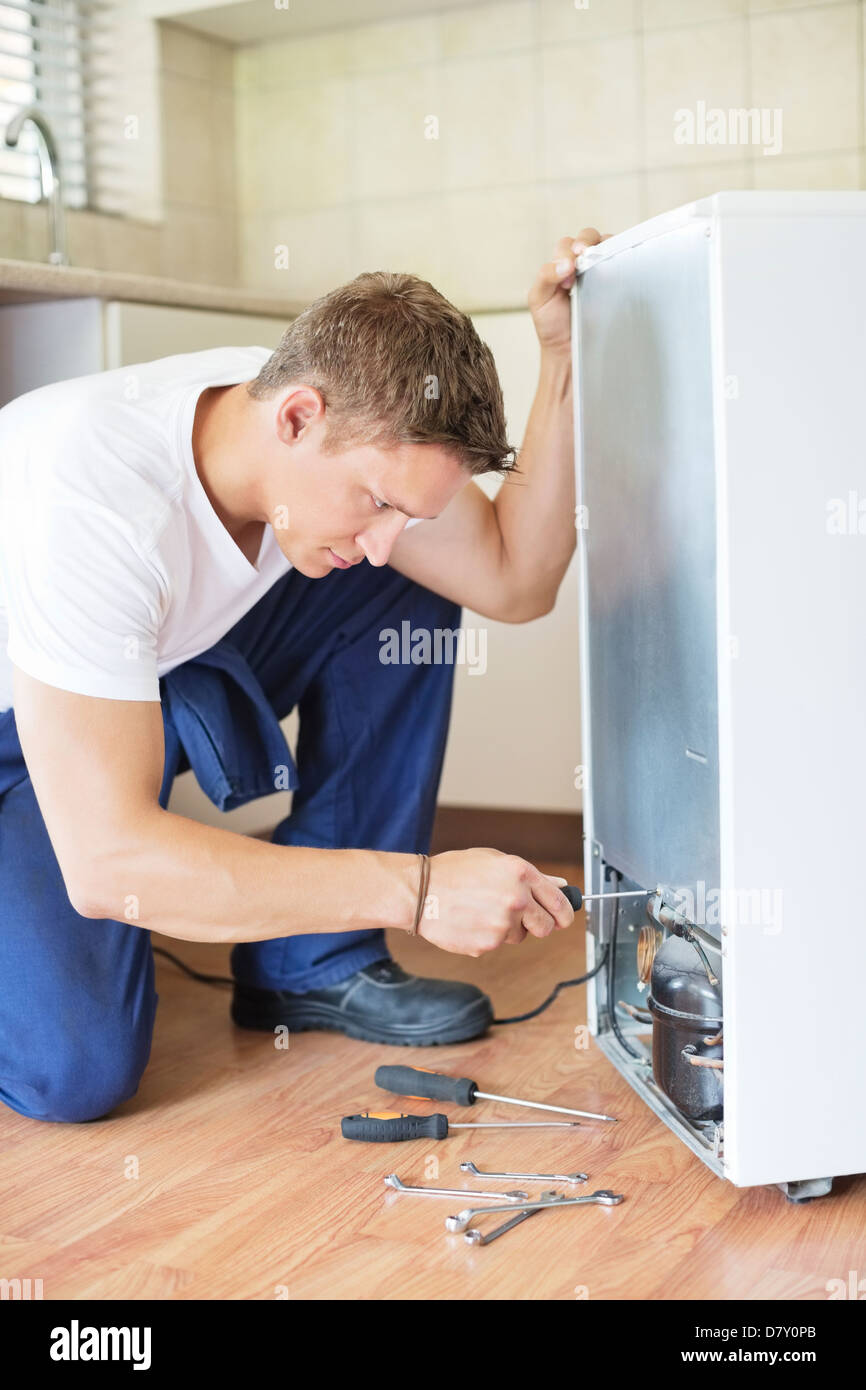 Repairman working on appliance in kitchen Stock Photo