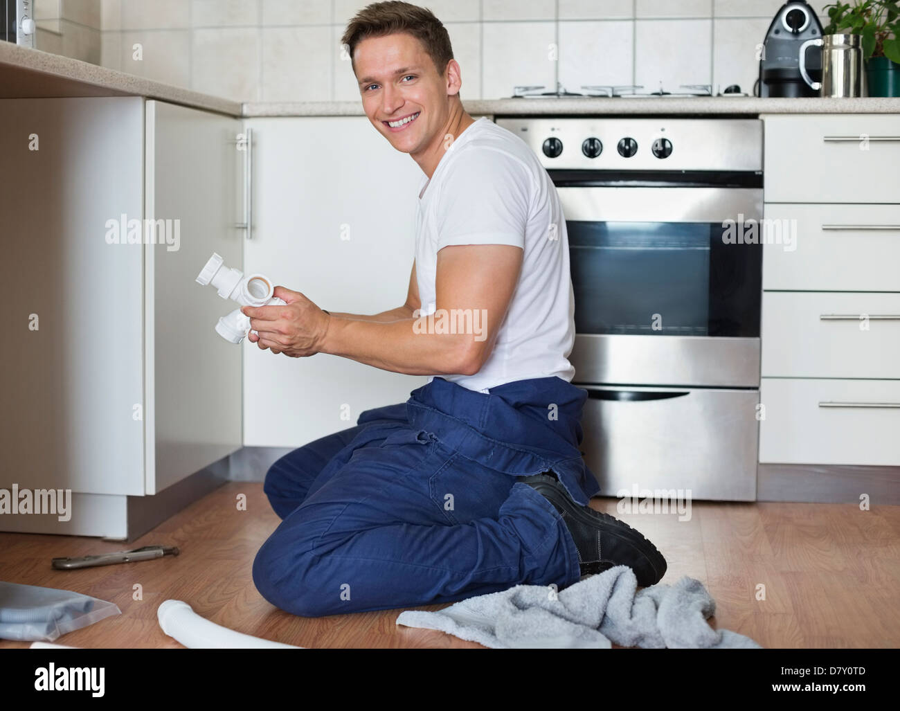 Plumber working on pipes under sink Stock Photo