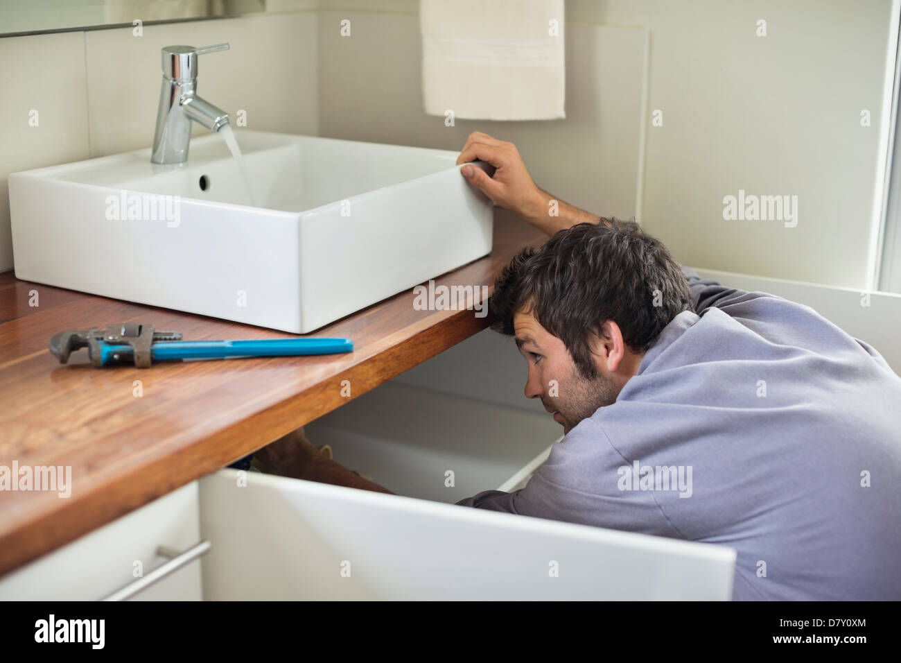 Plumber working under kitchen sink Stock Photo