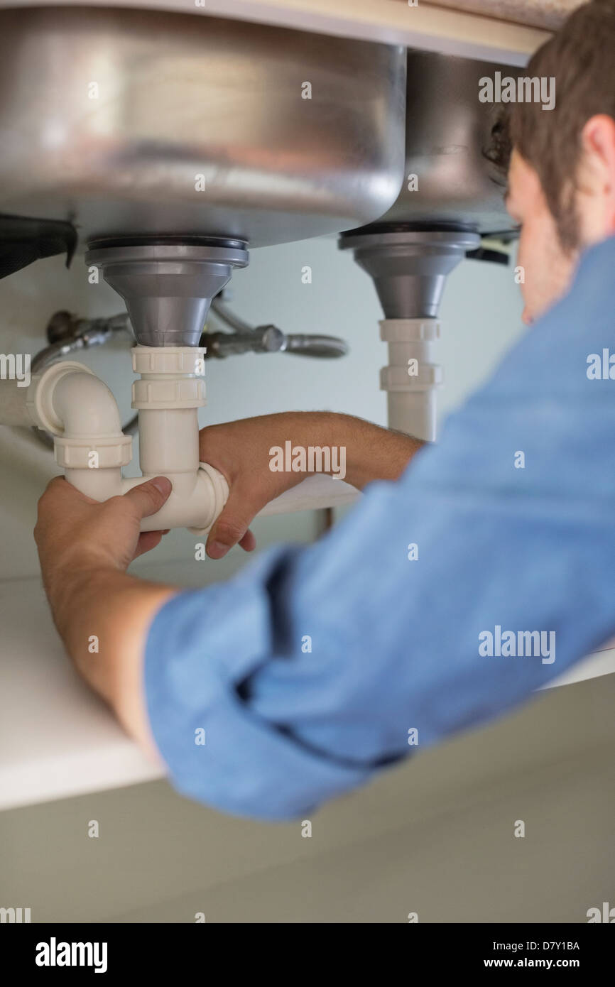 Plumber working on pipes under sink Stock Photo Alamy