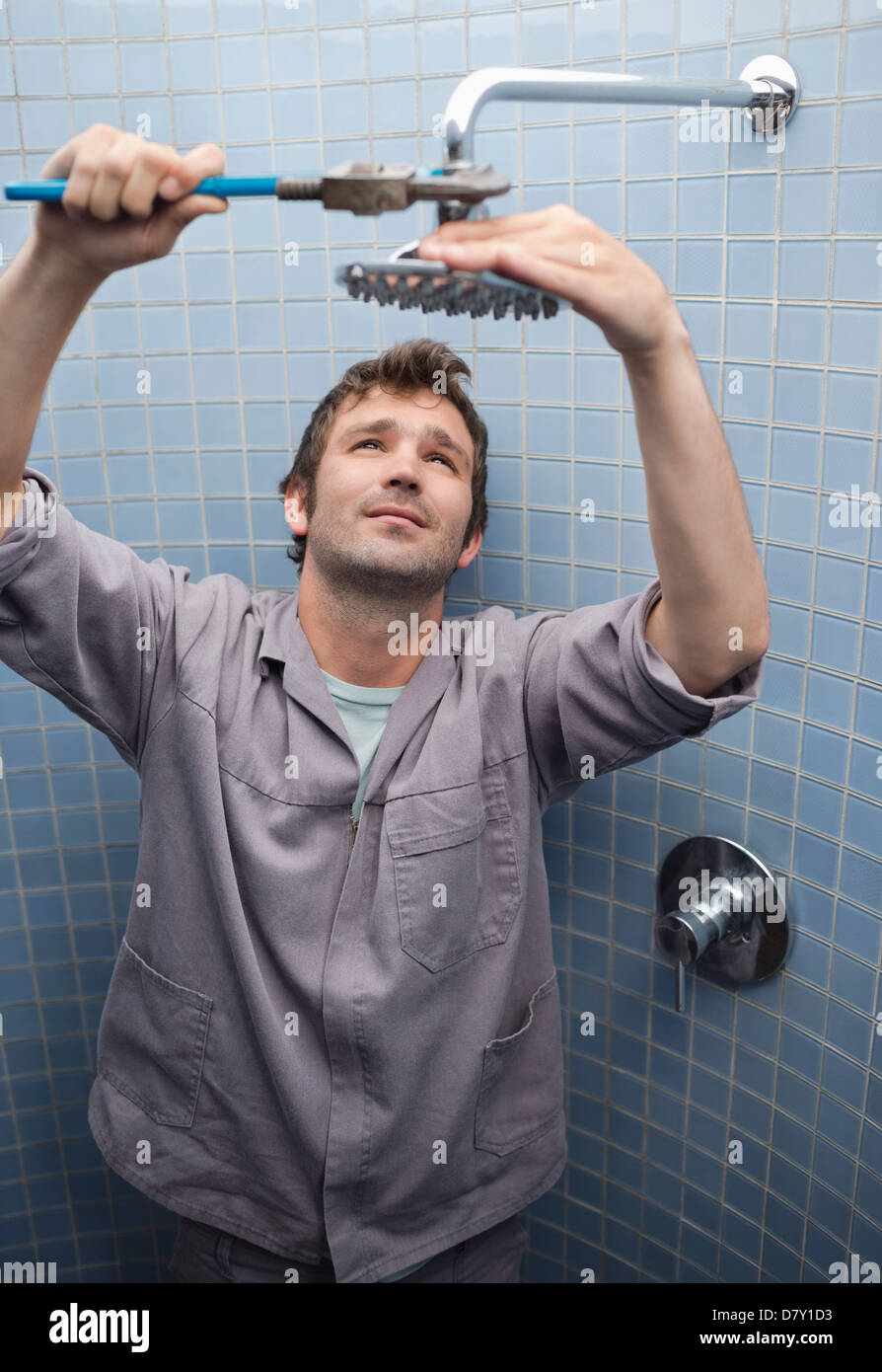 Plumber working on shower head in bathroom Stock Photo
