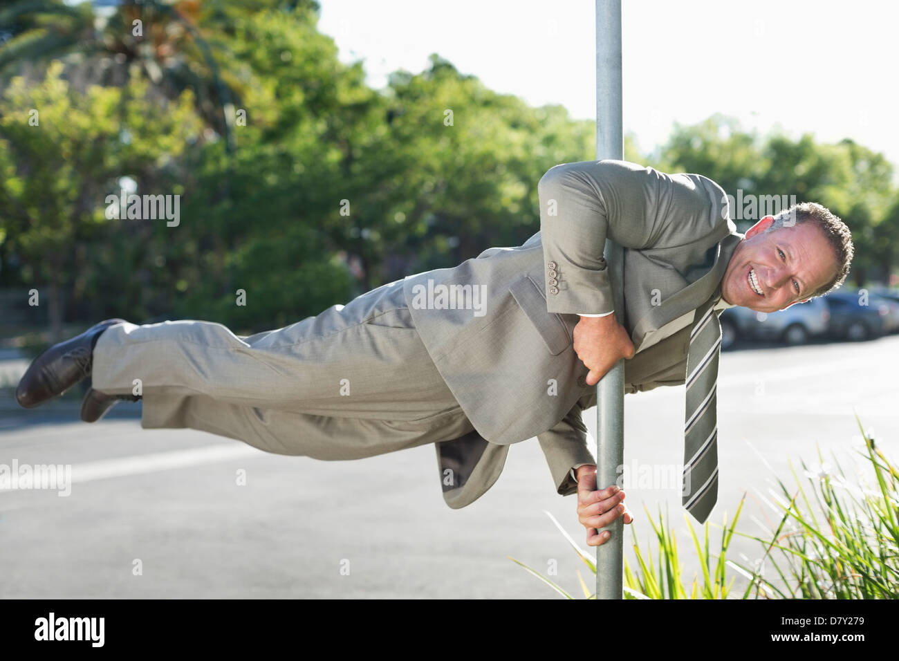 Businessman balancing on pole on city street Stock Photo