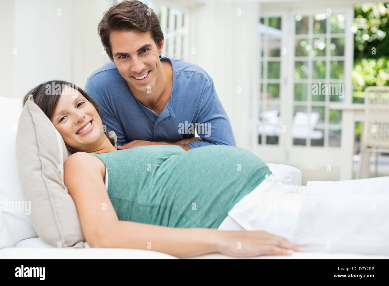 Man sitting next to pregnant woman resting on bed Stock Photo