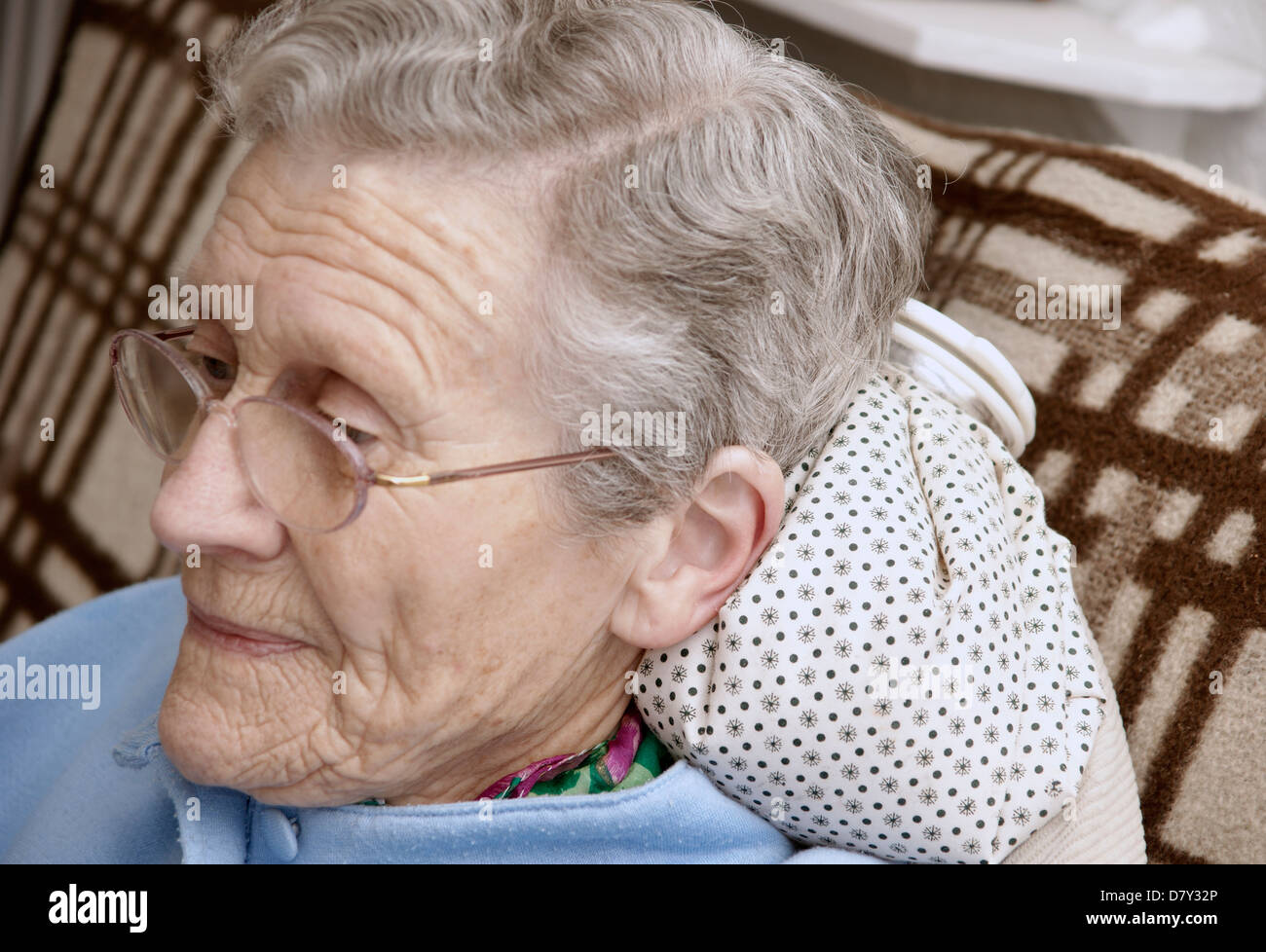 Elderly woman using a hot water bottle for neck & shoulder pain Stock Photo