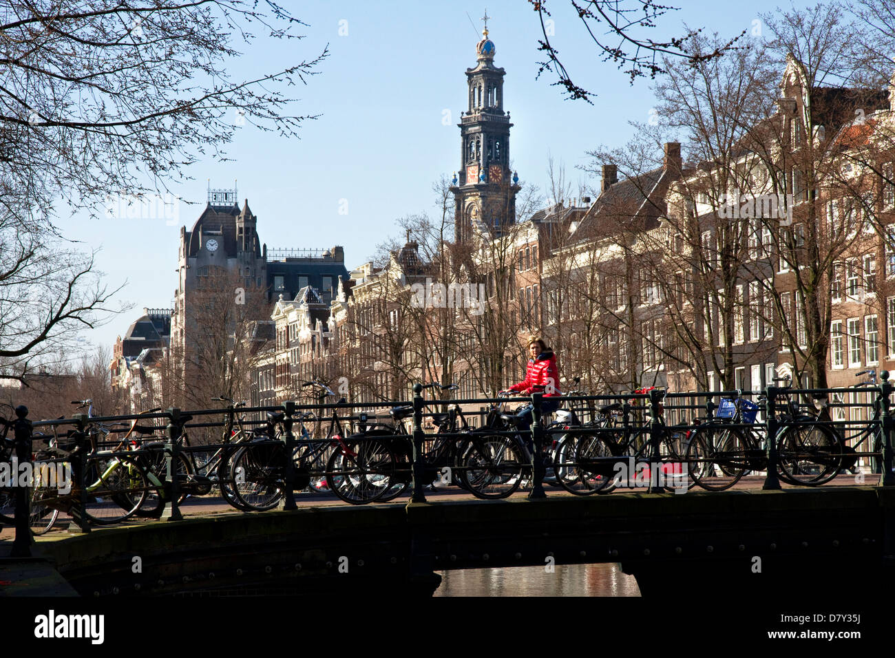 Cyclist on bridge, on Keizersgracht, Grachtengordel-west, Jordaan, central Amsterdam, Netherlands. Westerkerk tower beyond. Stock Photo