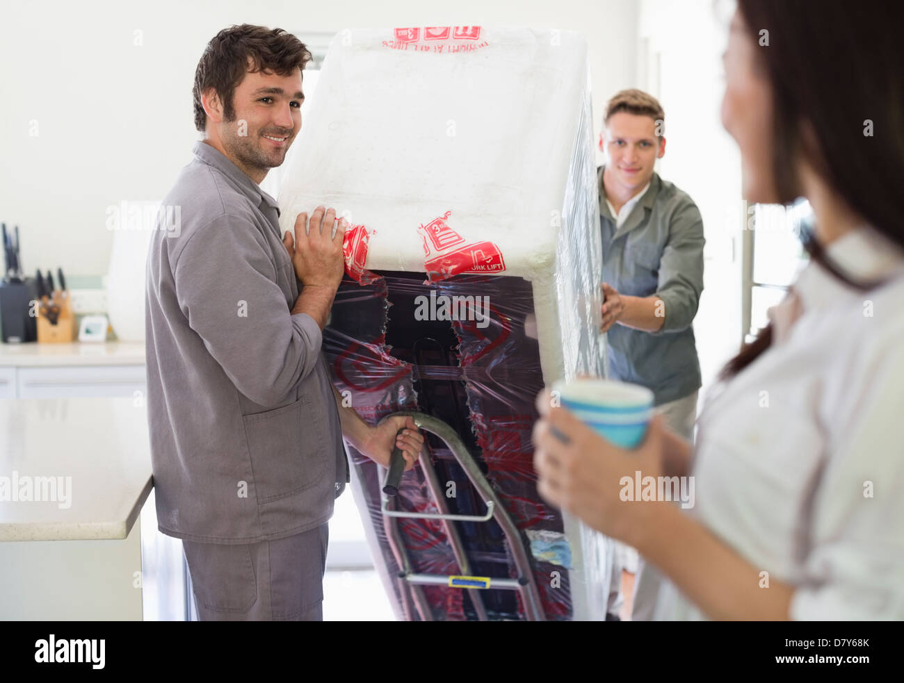 Workers delivering appliance in kitchen Stock Photo