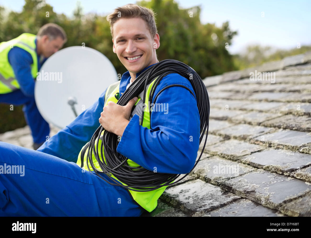 Workers installing satellite dish on roof Stock Photo