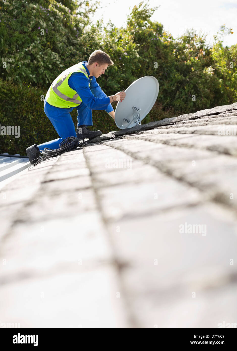 Worker installing satellite dish on roof Stock Photo