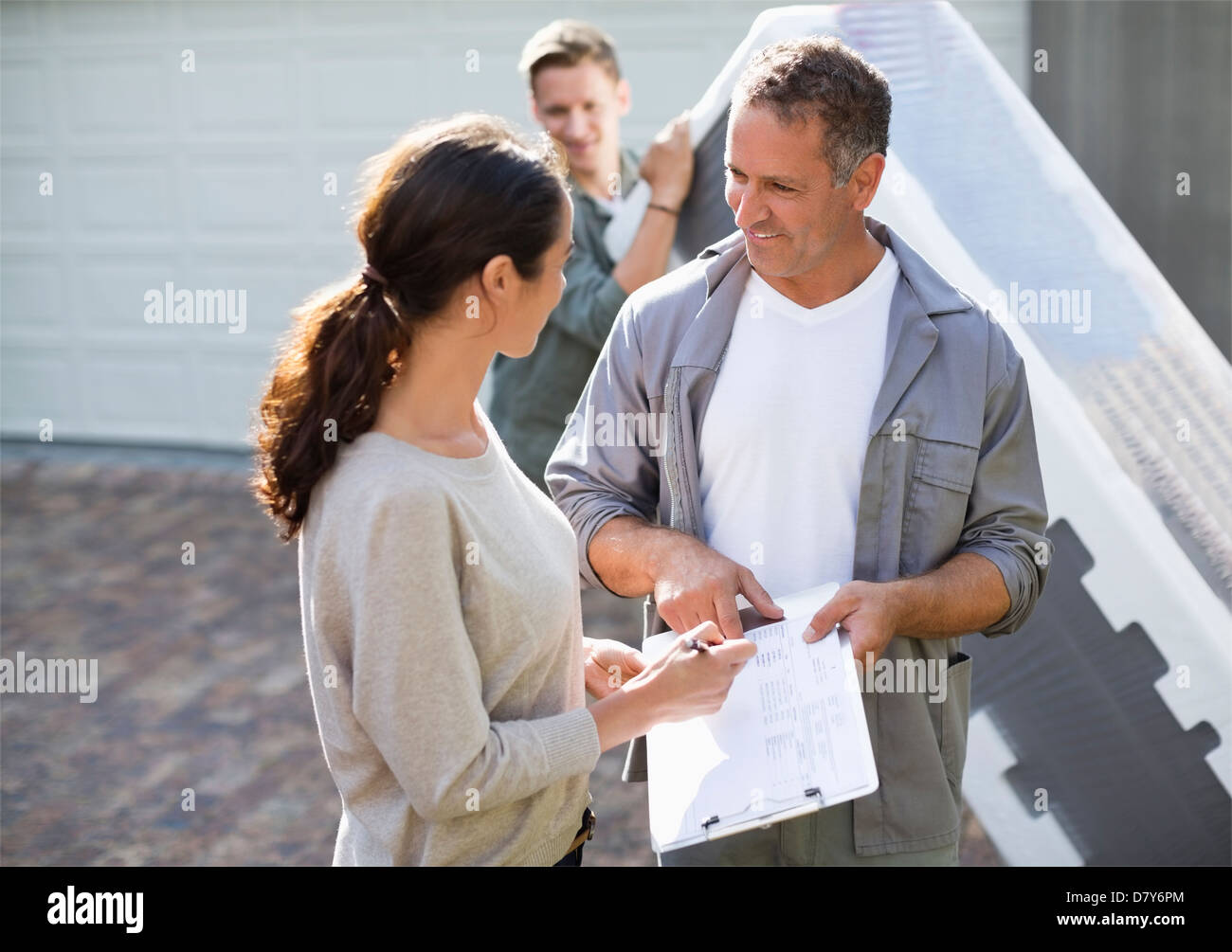 Woman signing for package in driveway Stock Photo