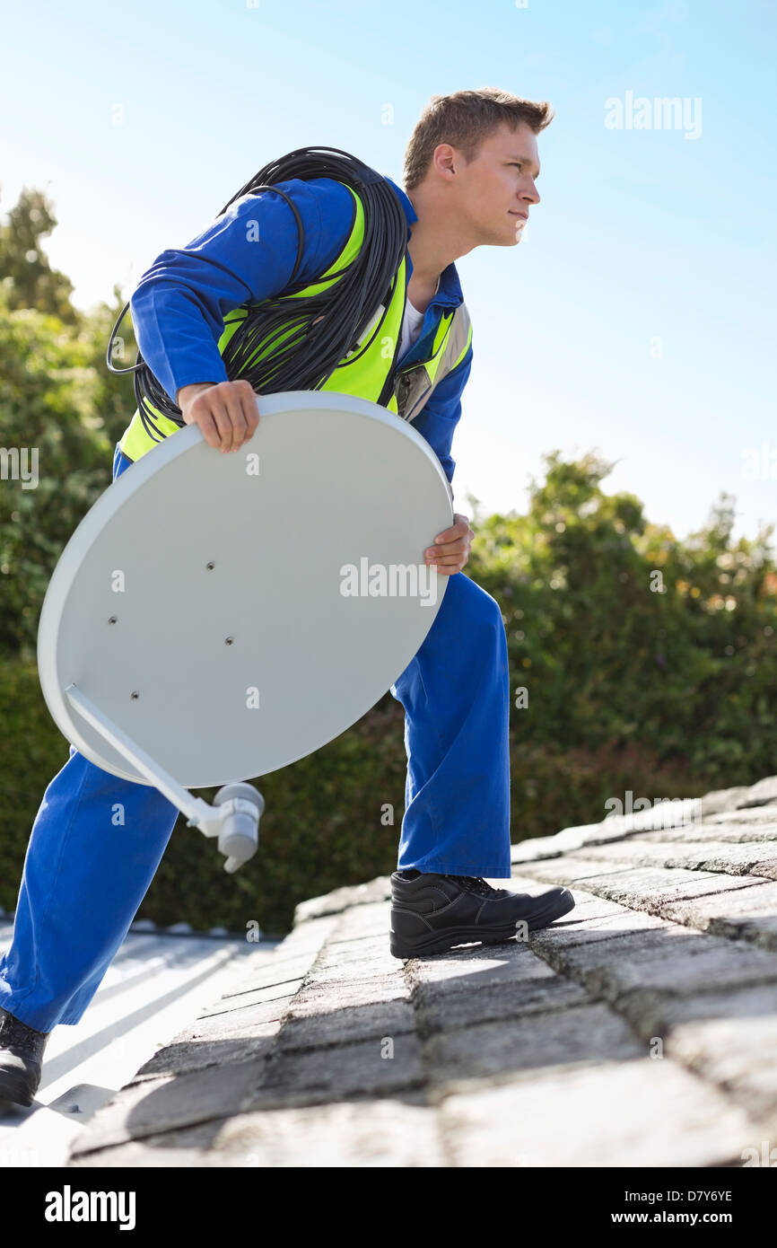 Worker installing satellite dish on roof Stock Photo