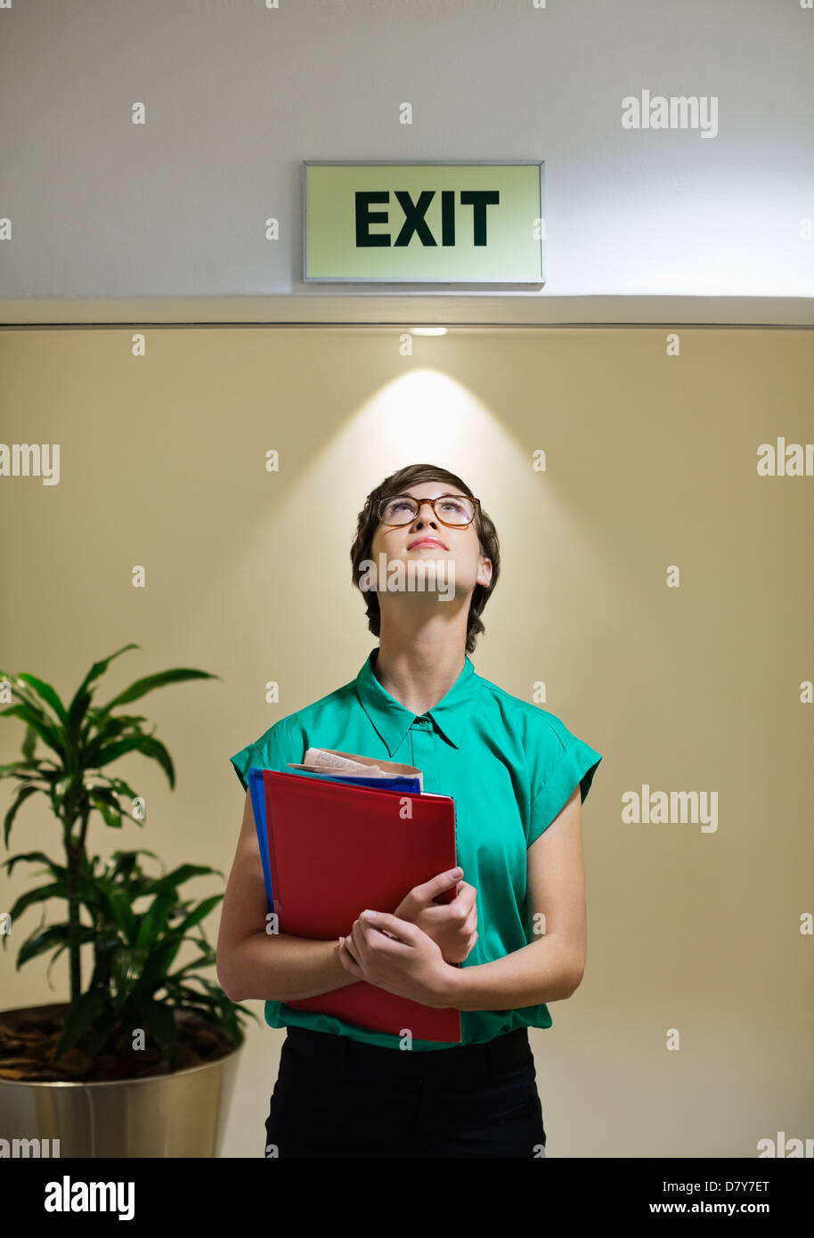Businesswoman standing under office ‘exit’ sign Stock Photo