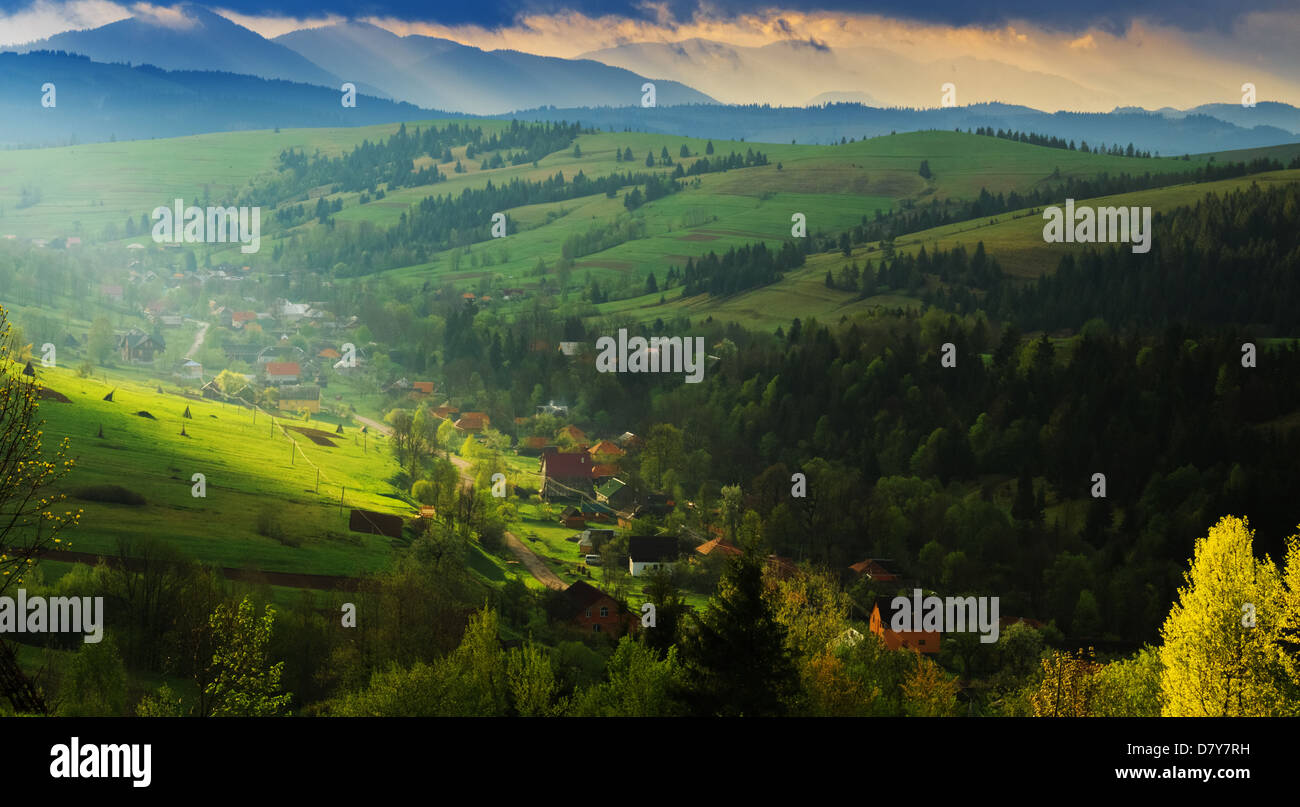 Spring morning rural landscape in the Carpathian mountains. Dramatic sky before dawn, a ray of light breaks through the clouds. Stock Photo