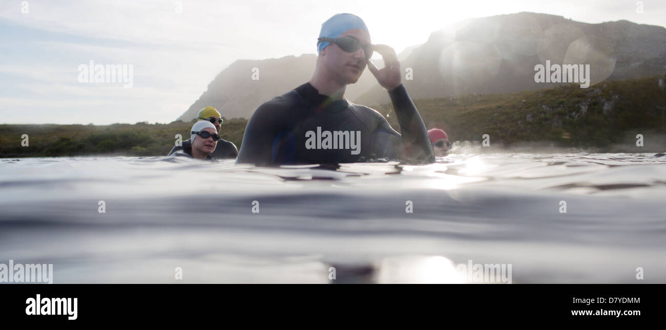Triathletes in wetsuits standing in water Stock Photo