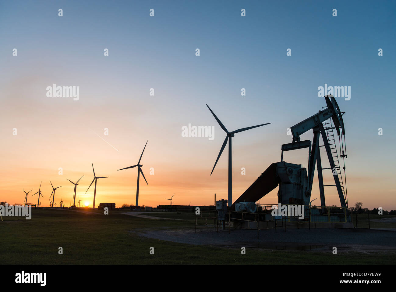Oil pump jack and wind turbines at sunset in central Oklahoma near Calumet. Stock Photo