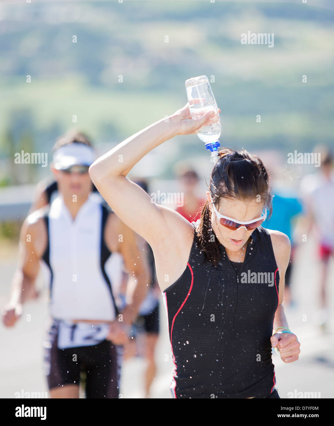 Runner pouring water on head in race Stock Photo