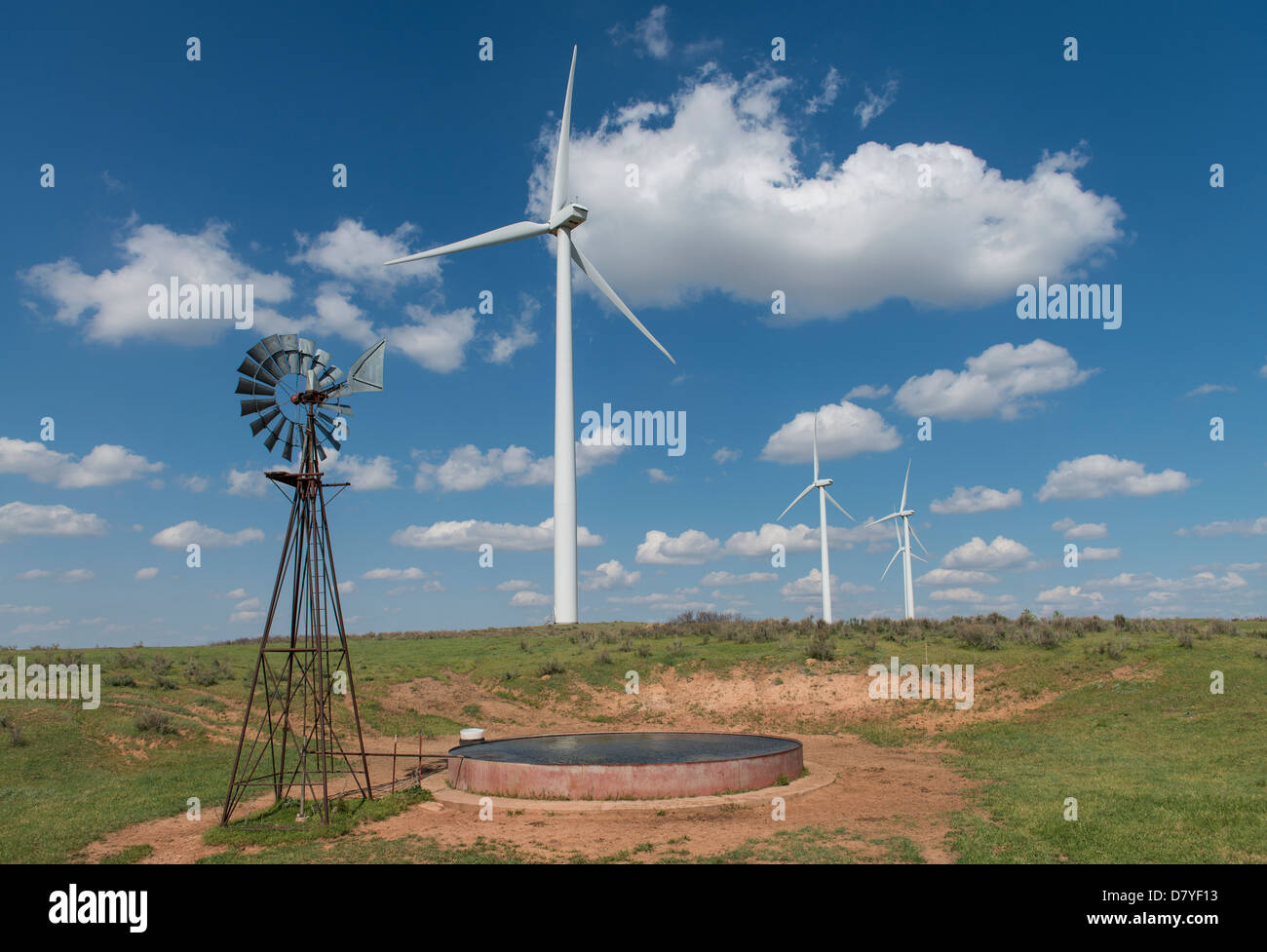 An old water pumping windmill sits beside electricity generating windmills in northwest Oklahoma Stock Photo