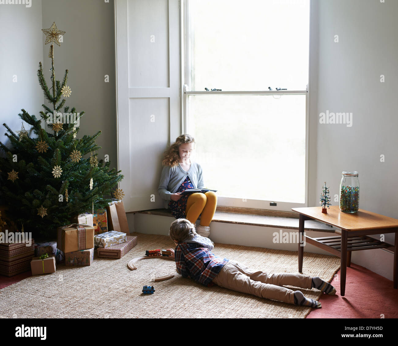 Children relaxing by Christmas tree Stock Photo - Alamy