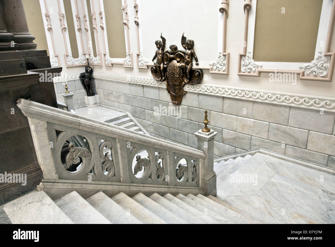 monumental interior marble staircase with carved leaf form balustrade & bronze coat of arms at landing Palacio Municipal Puebla Stock Photo