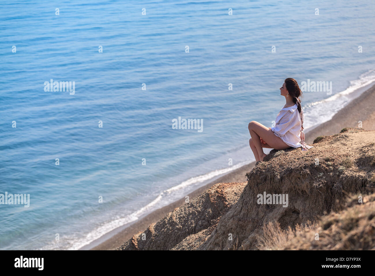 Girl sitting on a rock and looking at sea Stock Photo - Alamy