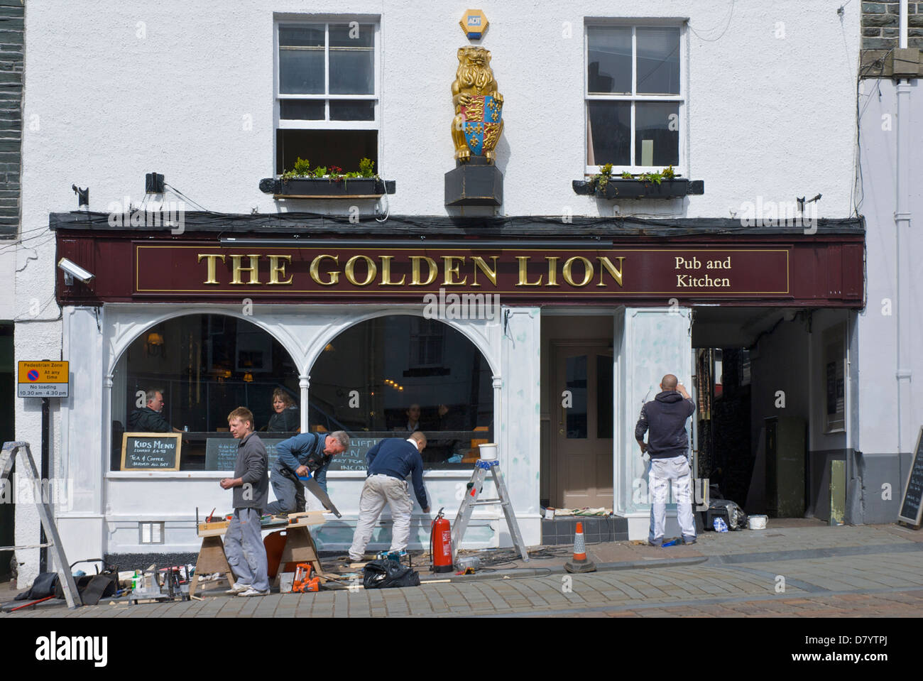 Men repainting the facade of the Golden Lion pub, in the town of Keswick, Lake District National Park, Cumbria, England UK Stock Photo