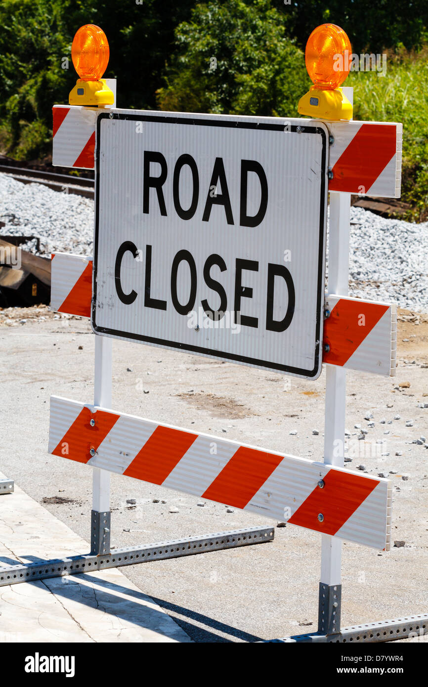 A single reflective road closed sign on a type III barricade with two ...